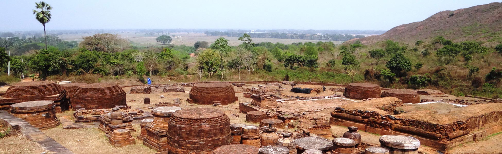Panoramic view of the ancient red brick stupas and monastic ruins at the Lalitgiri Buddhist complex in Odisha, India, surrounded by lush green hills. film shooting locations in Bapatla, video shooting locations in Bapatla, tv shooting locations in Bapatla, shooting locations in Bapatla