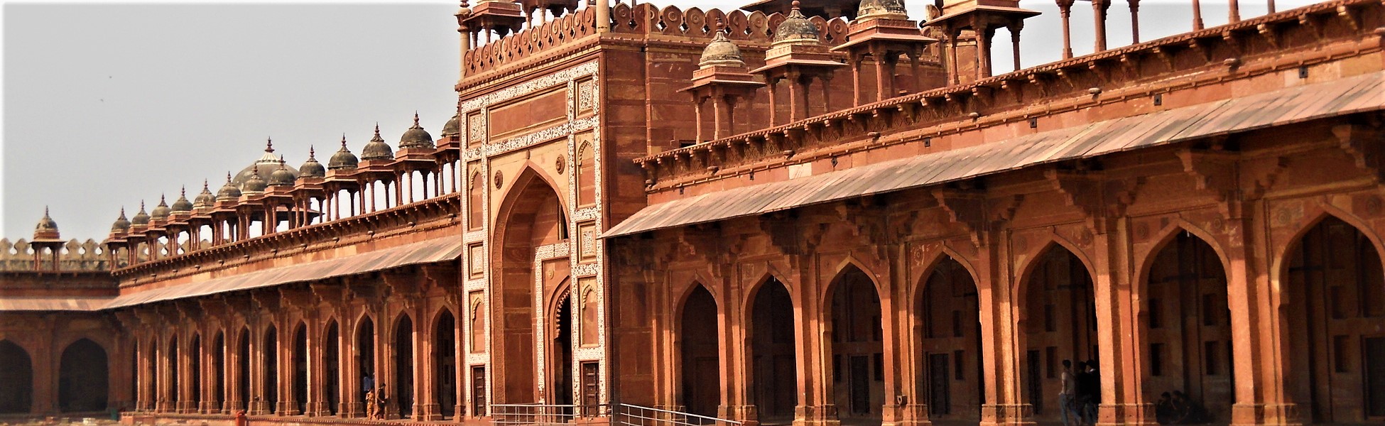 Symmetrical red sandstone arched corridors and decorative chhatris of the historic Jama Masjid courtyard at Fatehpur Sikri, a premier Mughal-era film shooting location in Uttar Pradesh, India. fixer in Bareilly, film fixer in Bareilly, media fixer in Bareilly, movie fixer in Bareilly, production fixer in Bareilly, line producer in Bareilly