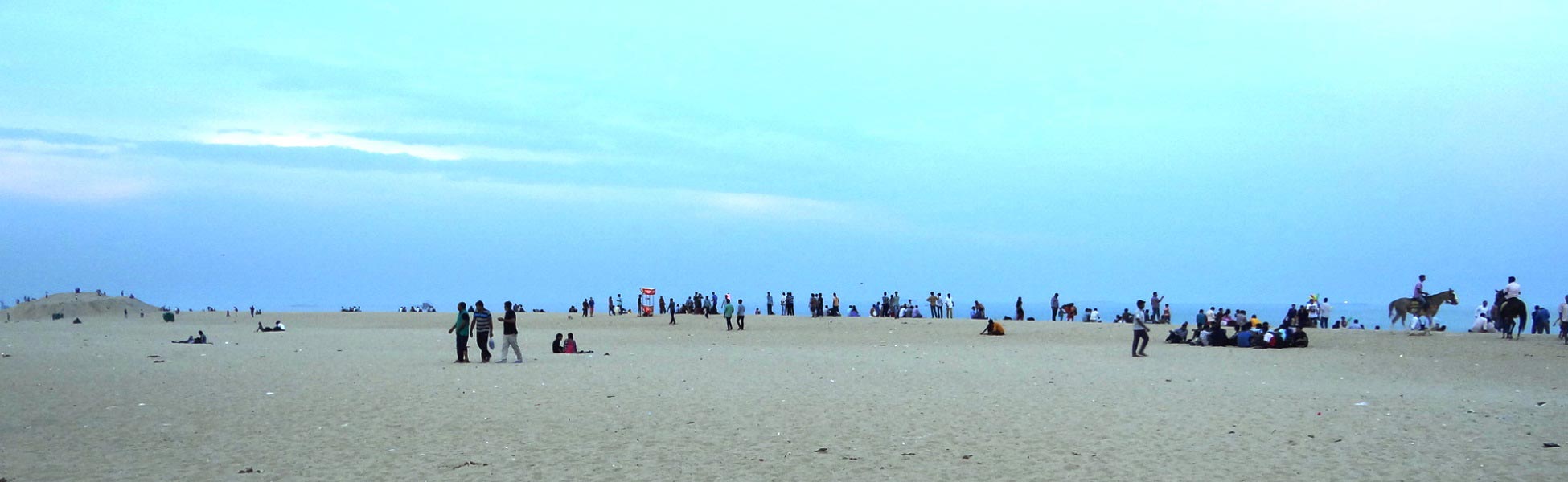 Wide-angle panoramic view of Marina Beach in Chennai during blue hour, showing film shooting location potential with wide sandy shores, local crowds, and horse riders under a vast sky. film shooting locations in Bastar, film shooting locations in jagdalpur, video shooting locations in Bastar, video shooting locations in jagdalpur, tv shooting locations in Bastar, tv shooting locations in jagdalpur, shooting locations in Bastar, shooting location in jagdalpur