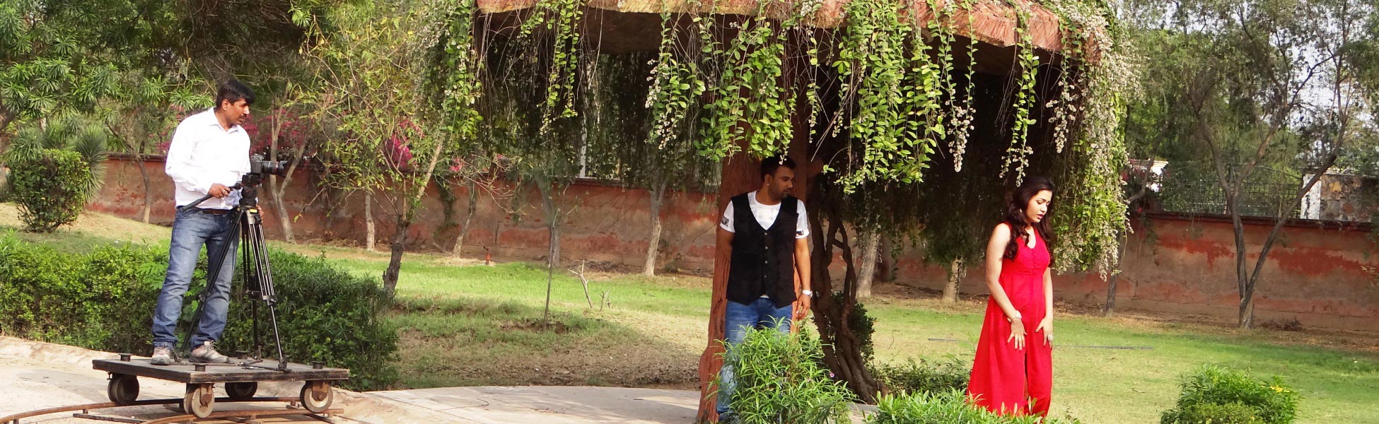 Trisna Films production crew operating a cinema camera on a dolly rail track during a outdoor music video shoot in a Delhi garden with actors. fixer in Bathinda, film fixer in Bathinda, media fixer in Bathinda, movie fixer in Bathinda, production fixer in Bathinda, line producer in Bathinda