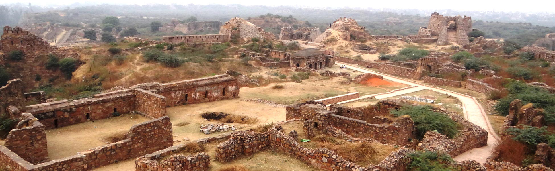Panoramic aerial view of the 14th-century stone ruins, ramparts, and weathered pathways of Tughlaqabad Fort in Delhi, India, showcasing ancient fortification architecture ideal for period film shoots. film shooting locations in Bengaluru South, video shooting locations in Bengaluru South, tv shooting locations in Bengaluru South, shooting locations in Bengaluru South