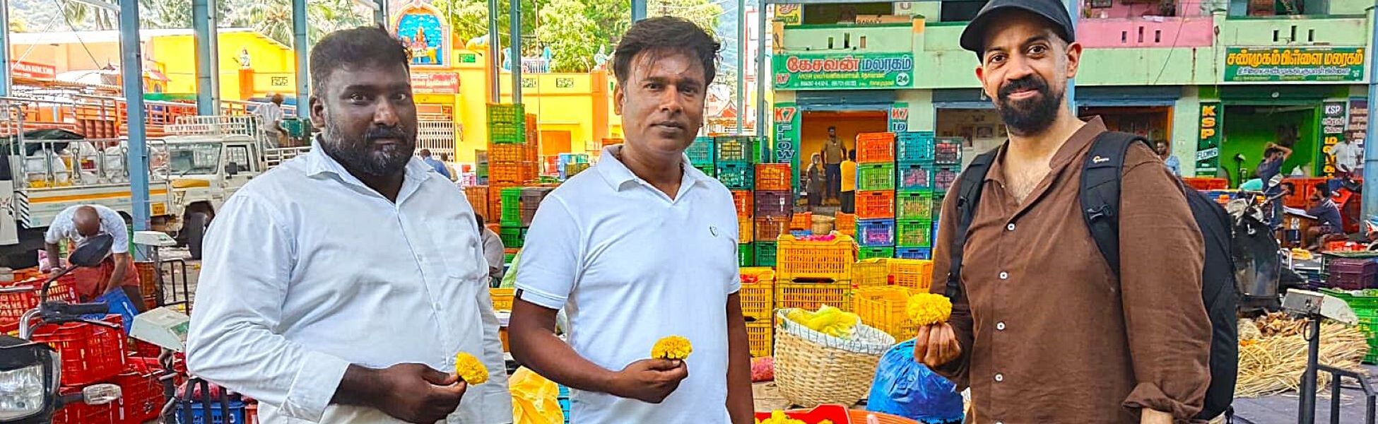 Trisna Films® documentary production team on-location at the Thovalai Flower Market in Nagercoil, Kanyakumari, Tamil Nadu. The crew is seen holding traditional marigold flowers while providing production support and location fixing for a documentary project in South India. filmmaking workshop in india, cinematography workshop in india, camera workshop in india, editing workshop in india, vfx workshop in india, animation workshop in india, photography workshop in india, direction workshop in india, script writing workshop in india