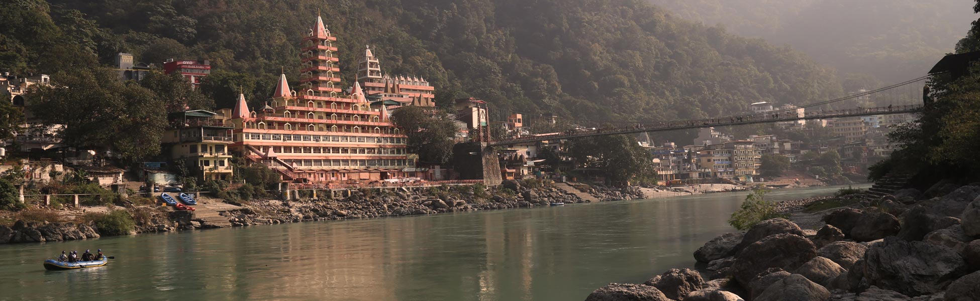 Scenic film shooting location along the holy River Ganges in Rishikesh, Uttarakhand, featuring the iconic Tera Manzil Temple and a suspension bridge against a lush mountainous backdrop. film shooting locations in Antigua and Berbuda, video shooting locations in Antigua and Berbuda, tv shooting locations in Antigua and Berbuda, shooting locations in Antigua and Berbuda