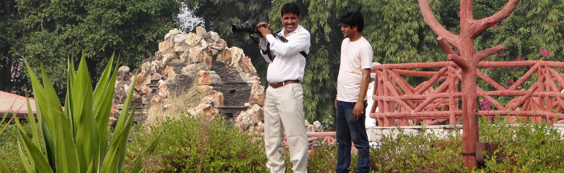 Professional cinematographers from Trisna Films® operating a DSLR rig on a lush outdoor film set. Featuring lead filmmaker capturing high-definition footage amidst tropical landscaping and rock formations for a documentary project. fixer in Anuppur, film fixer in anuppur, media fixer in anuppur, movie fixer in anuppur, production fixer in anuppur, line producer in Anuppur