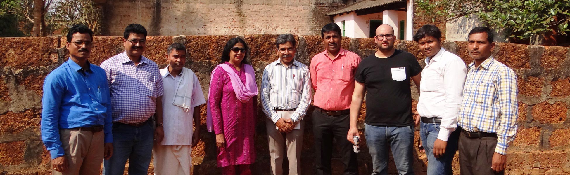 Group photo of the British and Indian film production crew standing against a traditional stone wall in Odisha, India, during the shoot for the Odisha Tourism CNN television campaign. filmmaking workshop in india, cinematography workshop in india, camera workshop in india, editing workshop in india, vfx workshop in india, animation workshop in india, photography workshop in india, direction workshop in india, script writing workshop in india