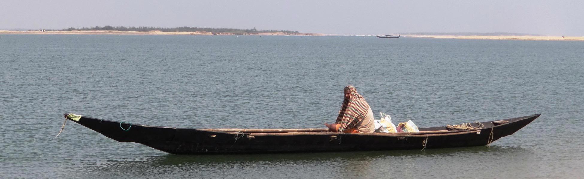 A traditional long wooden boat floating on the serene backwaters of Chilika Lake in Odisha, India—a scenic film shooting location captured by Trisna Films®. film shooting locations in Bageshwar, video shooting locations in Bageshwar, tv shooting locations in Bageshwar, shooting locations in Bageshwar